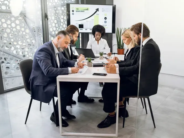 Executives review charts and documents at a small table during a presentation, demonstrating services on City Directory Guide